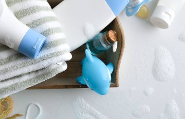 Aksesuar ve ürünlerle dolu banyo için beyaz masadaki su ve köpüklü bebek bakımı. Üst görünüm.