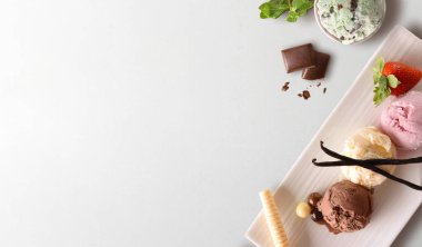 Dondurma toplarının arka planında çeşitli tatlar ve beyaz masada izole edilmiş malzemeler var.