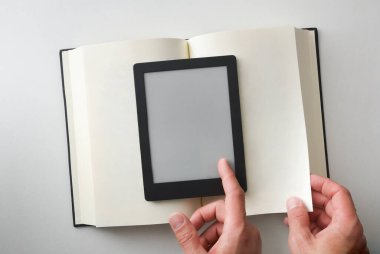 Elektronik kitaptaki okuma kavramı, kağıt üzerindeki kitapla ve her iki nesnenin de sayfasını çeviren ellerle karşılaştırılır. Üst görünüm.
