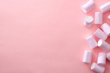 Sağ tarafta pembe arka planda pembe tüp şeklinde yumuşak şekerler. Üst görünüm.