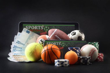 Çeşitli sporları temsil eden fiziksel ve çevrimiçi spor kavramı banknotlar, bahis fişleri ve mobil cihazlar ile izole edilmiş karanlık bir arka planda bahis uygulaması ve analizi ile.