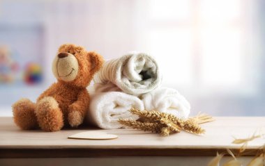 Havlular ve bornoz ahşap dolapta, mavi banyoda pencereli oyuncak ayıyla. Ön görünüm.