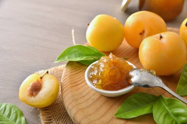 Tahta kesme tahtasında erik reçeli ve ahşap masada meyve dolu bir kavanoz. Yüksek görünüm