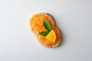 Turuncu reçelli tost, beyaz masada meyvelerle süslenmiş. Üst görünüm.