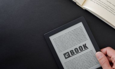 E-kitap okuma konsepti, siyah masanın üzerinde el ele tutuşan kitap ve geleneksel kağıt kitabı açmak. Üst görünüm