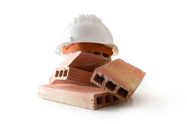 Tuğla yığını ve beyaz miğfer beyaz arka planda izole edilmiş beyaz üste. Ön görünüm.