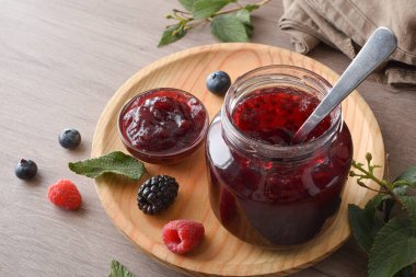 Ormandaki meyve reçel kavanozları ahşap bir tabakta meyve ve yapraklarla bezenmiş. Yüksek görünüm.