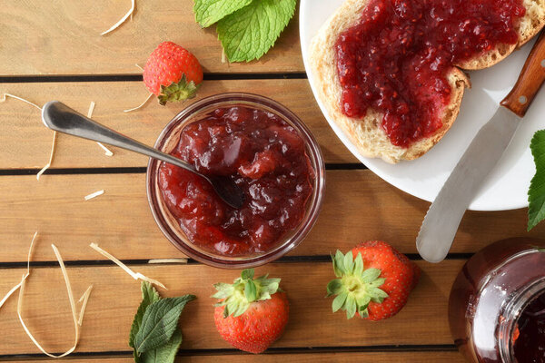Природный завтрак с клубничным джемом на белой тарелке на деревянном столе с фруктами. Вид сверху.