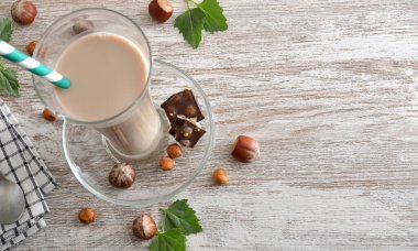 Tahta masada fındık ve yapraklarla serinletici fındık içeceği içeren cam parçaları. Üst görünüm.