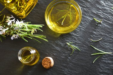 Cam kaplardaki biberiye yağının ayrıntıları ve masa üzerinde taze dallar. Üst görünüm.