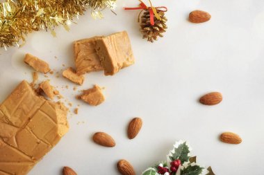 Geleneksel yumuşak bademli fındık, beyaz masa üzerinde gofretle kaplı, doğal badem ve Noel süsüsüyle dolu. Üst görünüm.