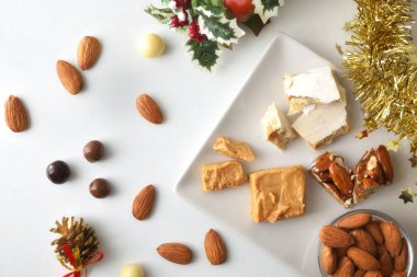 Tabağın ayrıntıları çeşitli porsiyonlarda beyaz masada doğal bademler, çikolata topları ve Noel süslemeleri ile birlikte. Üst görünüm.