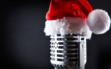 Detail of old microphone with a Santa hat on top, isolated on a black background. Side view. clipart