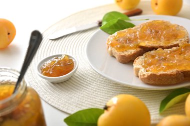 Mutfak tezgahı, kahvaltı tabakta erik reçeli, kavanozlar ve meyvelerle hazırlandı. Yüksek görünüm.