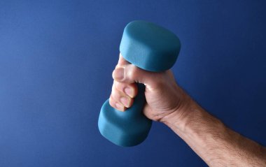 Mavi eğimli arka planda izole edilmiş kas güçlendirme sporu için mavi neoprene halteri tutan el..