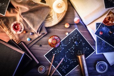 Tablolar, çizimler, aletler ve kitaplar gibi eski astroloji çalışmalarının kavramı ahşap masa üzerinde mumlarla. Üst görünüm.