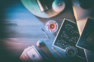 Takımyıldızlı haritalı esrarengiz astrolojik arka plan detayları, kehanet kartları ve sihirli atmosferli ahşap masa üzerindeki eski nesneler. Üst görünüm.
