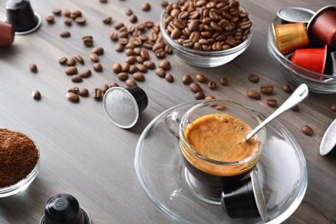 Kahve bardağı ve kahve tozu için kapsüllü kapsülleri olan ahşap bir bankta cam bir fincanda Espresso kahvesi. Üst Görünüm.