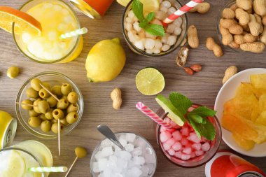 Meşrubatlı bardaklar ve kavanozlu ve meyveli ahşap bir masada abur cuburlu kaplar. Üst görünüm.