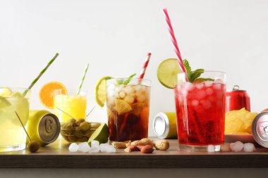 Farklı aromalı, buzlu ve ahşap masa üzerinde aperatifleri ve beyaz izole edilmiş arka planı olan çeşitli kadehlerin ayrıntıları. Ön görünüm.