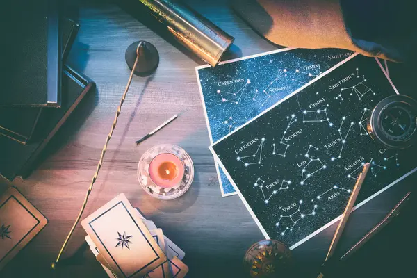 Takımyıldızları, kehanet kartları ve tahta masa üzerinde kitaplarla ve büyülü atmosferle birlikte eski nesneler bulunan haritalı esrarengiz çalışma ve öngörü arka planı ayrıntıları. Üst görünüm.