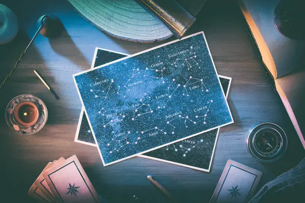 Astrolojik çalışma arkaplanı ve tahmini haritalar ile ahşap bir masanın ortasındaki takımyıldızlarla klasik nesneler ve sihirli atmosferli aletler. Üst görünüm.