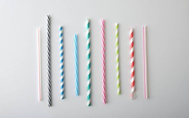 Beyaz bir masada izole edilmiş farklı desenlere ve renklere sahip boru şeklinde pipet koleksiyonu. Üst görünüm.