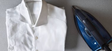 Ütülenmemiş, buruşuk gömlekli buhar ütüleme konsepti diğer tarafta ütü masasındaki buhar ütüsünün yanında. Üst görünüm.