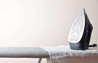 Beyaz gömlekli ve arka planda hafif izole edilmiş gri ütü masasında duran ütü konsepti. Ön görünüm.