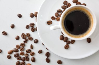 Kahve fincanı beyaz seramik bardakta kahve çekirdekli beyaz masada. Üst görünüm.