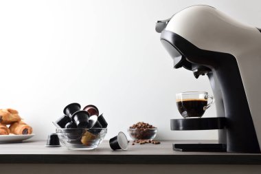 Tahta bir bankta, kapsüllü, fasulyeli ve pastalı espresso makinesinde, beyaz arka planda izole edilmiş taze demlenmiş kahve. Yan görünüm.