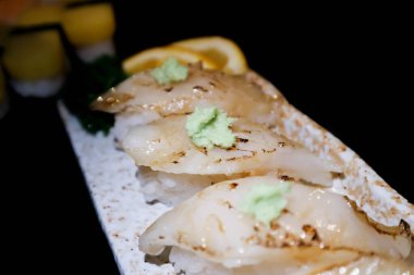 Suşi ya da achiwa suşisi ya da balık suşisi, taneli pilav ya da siyah arka planda balık rulosu.