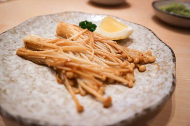 Karıştırılmış altın iğne mantarı ya da kızartılmış mantar ve limon.