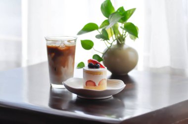 Çilekli pasta ya da çilekli pasta üzerine çilek ve yaban mersini sosu ve buzlu kahve.