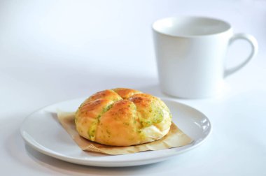 Peynirli çörek, krem peynirli sarımsaklı ekmek ya da Kore krem peynirli sarımsaklı çörek ya da krem peynirli sarımsaklı çörek ve beyaz arka planda sıcak içecek.