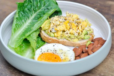 Yumurtalı ekmek ve yumurtalı avokado soslu yumurta, marul ve badem servis için.