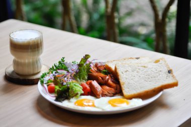 Kahvaltı ya da ekmek yanında yumurta, sosis ve sebze ve sıcak kahve.