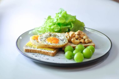 Kahvaltıda yumurta, fındık, üzüm ve marullu tost veya ekmek.