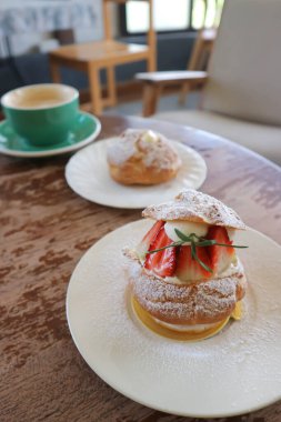 Choux kreması ya da kremalı pasta, ekinler ya da çilekli choux kreması ve kahve masanın üzerinde.