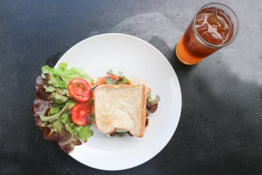 Jambonlu ve peynirli sandviç, salata ve portakallı sade kahve.