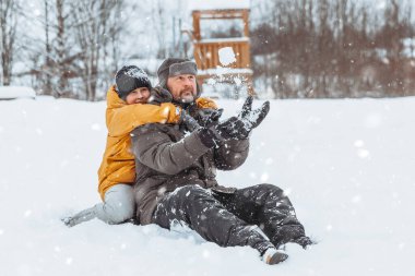 Baba ve kızı karlı arazide yürüyor, Aile kışın parkta yürüyor.