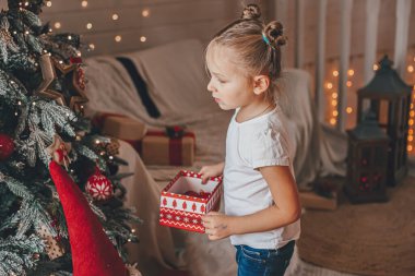 Şirin küçük kız bir Noel ağacı süslüyor. Mutlu Noeller ve yeni yıl tatilleri.