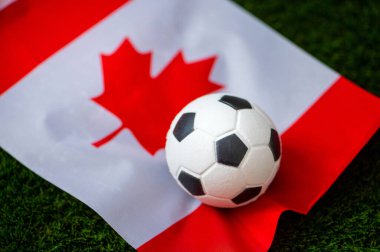 Kanada Milli Futbol Takımı. Ulusal Bayrak yeşil çimlerde ve futbol topunda. 2022 yılında şampiyonluk ve turnuva için futbol duvar kâğıdı. Dünya çapında maç.