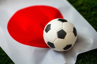 Japonya Milli Futbol Takımı. Ulusal Bayrak yeşil çimlerde ve futbol topunda. 2022 yılında şampiyonluk ve turnuva için futbol duvar kâğıdı. Dünya çapında maç.