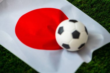 Japonya Milli Futbol Takımı. Ulusal Bayrak yeşil çimlerde ve futbol topunda. 2022 yılında şampiyonluk ve turnuva için futbol duvar kâğıdı. Dünya çapında maç.