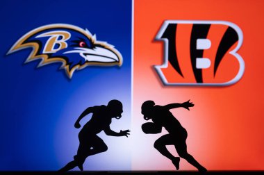 CINCINNATI, USA, JANUARY 10, 2023: Baltimore Ravens vs. Cincinnati Bengals. NFL Wild Card Round 2023, Silhouette of two NFL American Football Players against each other. Big screen in background clipart