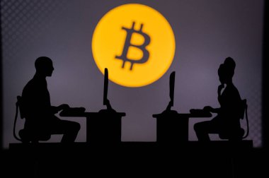 İngiltere, Londra. 30 Ocak 2023 Bitcoin (Bitcoin). Teknoloji dünyasına bir bakış: Arkalarında şirket logosu olan yazılım geliştiricilerinin silueti