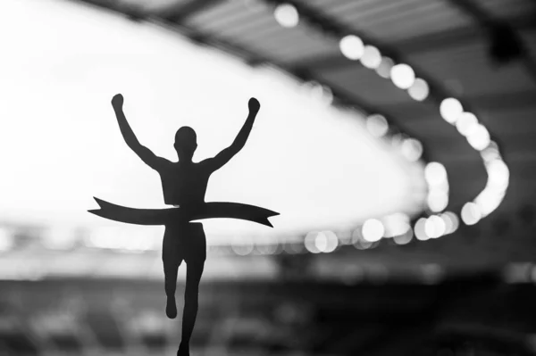 Stock image Silhouetted Runner Seizes Victory at Modern Athletics Stadium. An Inspiring Track and Field Competition Moment. Black and White photo for Summer Event in Paris 2024