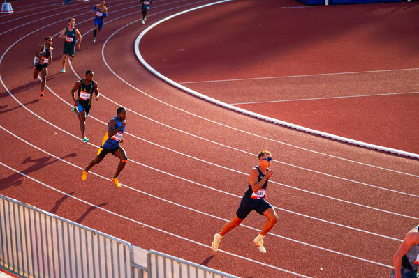 B. BYSTRICA, SLOVAKIA, JULY 20, 2023: Men Participate in 400m Sprint Amidst Beautiful Sunset Illumination at Track and Field Championship for Worlds in Budapest and Games in Paris