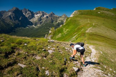 Genç yürüyüşçü High Tatras 'ta yürüyüş yaparken bir süre durur. Arka planda güzel manzara